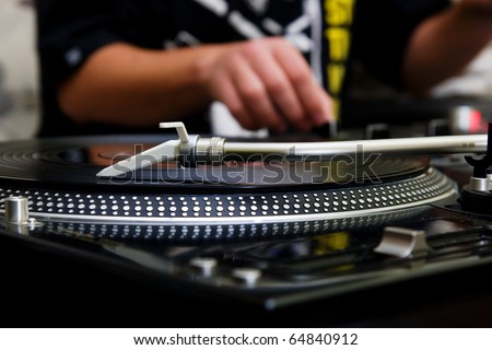 Focus on the professional turntable with a DJ adjusting the volume on controller