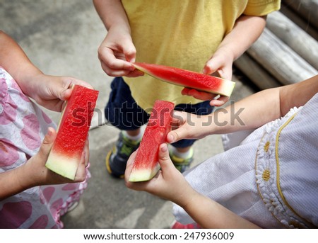 Hands three kids holding pieces of watermelon