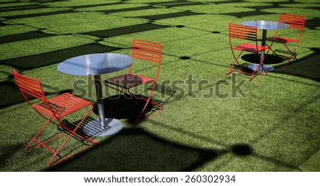Red chairs on green field with pattern of shadows