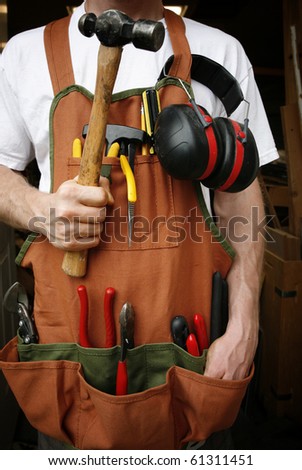 Handy man in front of work shop holding hammer
