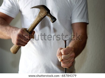 Muscular man, hammer and big nail
