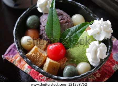 Japanese dessert with konjac jelly (konnyaku), brown sugar syrup, colored rice balls (mochi), sweet been paste (anko), sweet potato (satsumaimo), whipped cream, matcha ice cream and cherry tomato