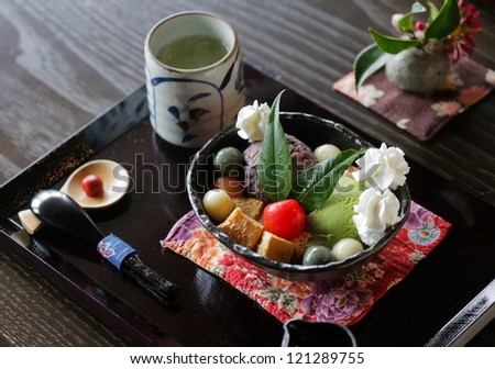 Japanese dessert with konjac jelly (konnyaku), brown sugar syrup, colored rice balls (mochi), sweet been paste (anko), sweet potato (satsumaimo), whipped cream, matcha ice cream and cherry tomato