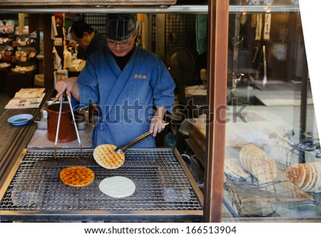 TAKAYAMA, JAPAN - CIRCA NOVEMBER 2012: Worker cooks giant senbei circa November 2012 in Takayama. Senbei, a type of Japanese rice crackers, are traditionally cooked by being grilled over charcoal.