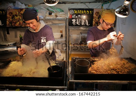 KOBE, JAPAN - DEC 14: Sobameshi, pan-fried ramen-style noodles with fried rice, being cooked by two at one of tens yatai, mobile food stalls, located by Kobe Luminarie on Dec 14, 2013 in Kobe, Japan.