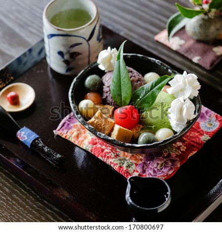 Japanese dessert with konjac jelly (konnyaku), brown sugar syrup, colored rice balls (mochi), sweet been paste (anko), sweet potato (satsumaimo), whipped cream, matcha ice cream, peeled cherry tomato