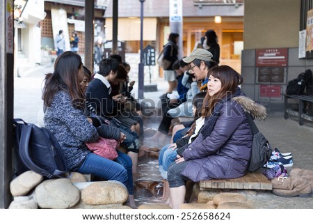 KOBE, JAPAN - FEBRUARY 14, 2015: Tourists enjoy a free foot bath (ashiyu) outside the larger of Arima Onsen\'s two public bath houses, Kin no Yu. Arima Onsen is one of Japan\'s three oldest hot springs.