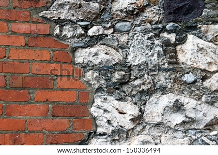 Red clay bricks and rugged, mostly white stones  come together in a masonry wall of a very old building.