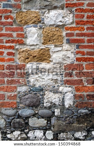 A colorful and interesting masonry wall with many textures combines red clay bricks and several varieties of stones.