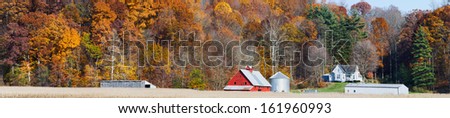 An Indiana farm with red barn is backed by a hillside full of colorful fall foliage in this panoramic photograph.