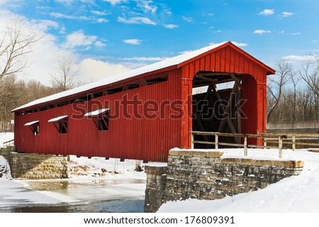 The Red Cataract Falls Covered Bridge Crosses Indiana\'S Mill Creek With A Snowy Landscape And Deep Blue, Cloud-Draped Sky.
