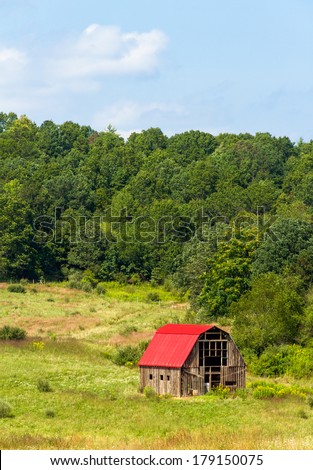 An old barn with a bright red roof punctuates farmland in the hills of western Virginia.