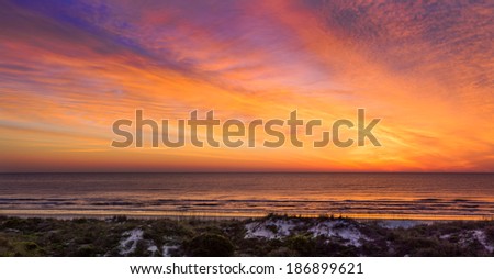 The rising sun illuminates the sky over the Atlantic Ocean with intense colors on the Florida coast.