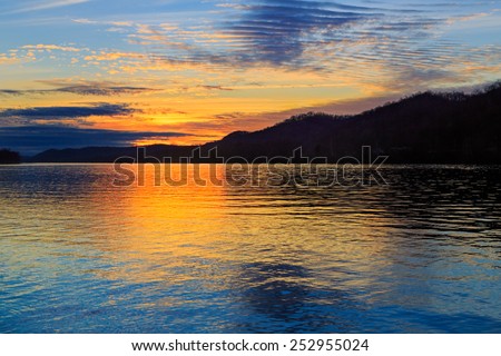 The setting sun silhouettes hills as it reflects upon the waters of the Ohio River as seen from Paden City, West Virginia.