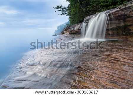 Elliot Falls, a small but beautiful waterfall on Miner\'s Beach at Michigan\'s Pictured Rocks National Lakeshore, spills over rock ledges and into Lake Superior after sundown.