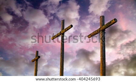 Three old rugged wooden crosses stand tall against an amazing and dramatic sky at sunset.