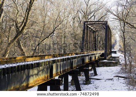 A train trestle, rusty and with icicles in the light of the setting sun