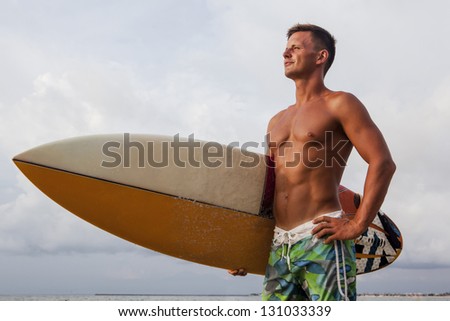 Confident professional surfer with surf board looking at ocean