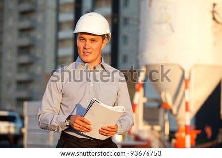 portrait of well-dressed man in hard hat standing against the construction