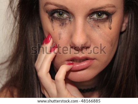 Emotional portrait of the beautiful young crying woman with tears on her face