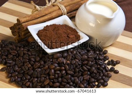Pitcher of milk, coffee and cocoa beans on a bamboo cutting board