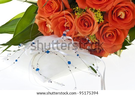 necklace and orange roses on a white background