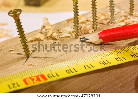 Screws bolted to the plank and tape measure with red pencil
