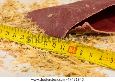 Sawdust, a ruler and abrasive (sandpaper) on desktop