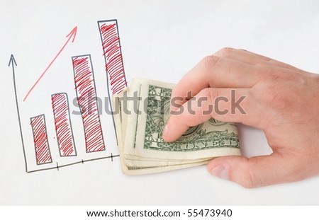 Holding money in hand near drawing graph over white paper