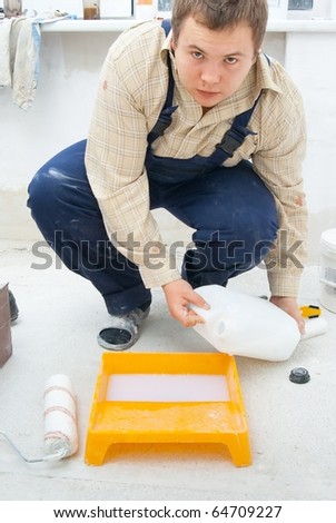 young workman pouring paint from a bucket