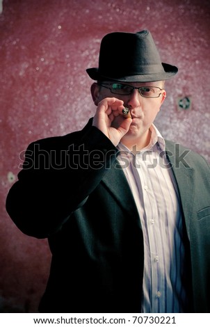 man in black suite on red wall with cigar. Gangster theme