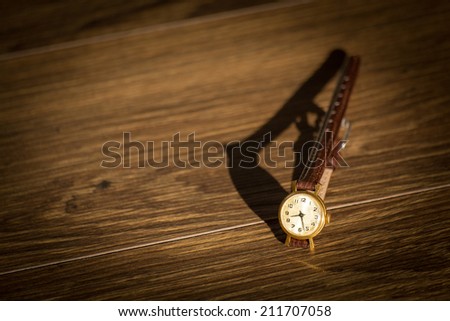 Old wristwatch with scratches on glass and leather strap on wooden background