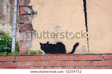 Black cat painted on a brown brick wall