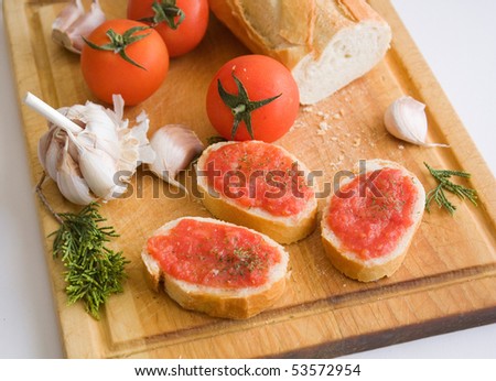 Slices of bread with a tomato paste, parsley and tomatoes with garlic on a kitchen board.