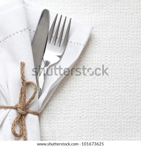 Knife and fork with white linen tied up with string Knife and fork with white linen tied up with string