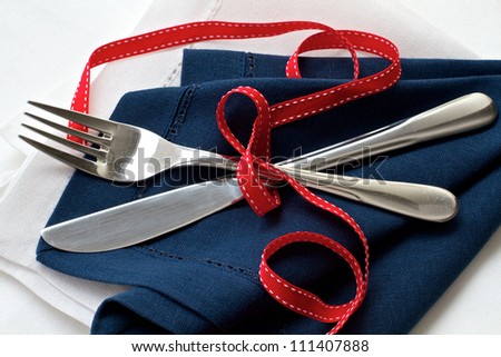 Navy and white serviette with cutlery tied with a red ribbon