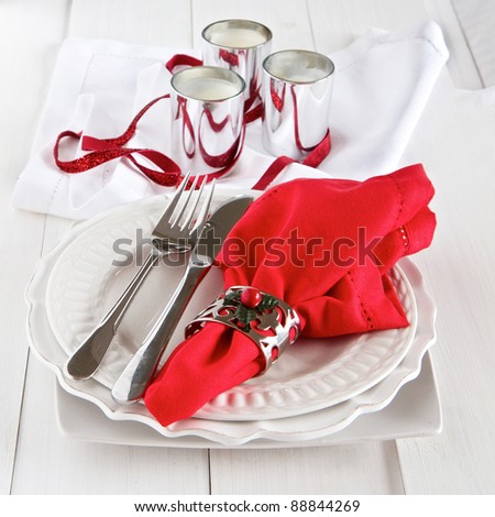 Table setting with silverware, red napkin, candles and decoration for Christmas