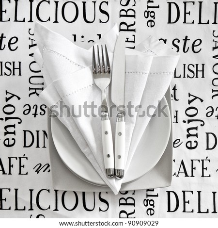 Table setting with cutlery and crockery on printed linen tablecloth