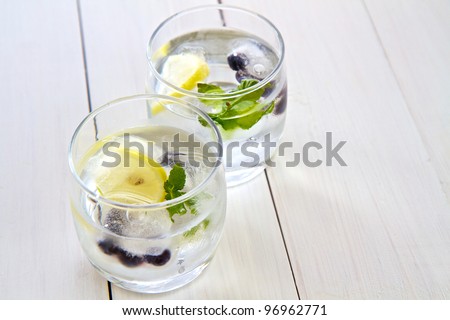 Ice cubes with fruit and mint in a glass of water with space for text