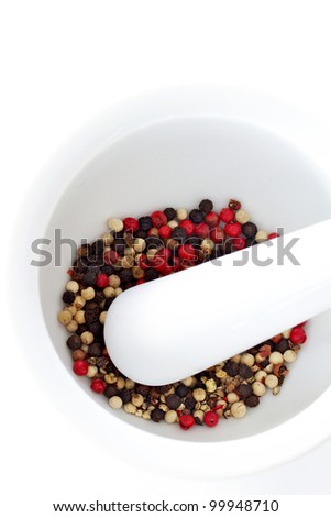 Red black and white peppercorns in a pestle and mortar isolated on a white background