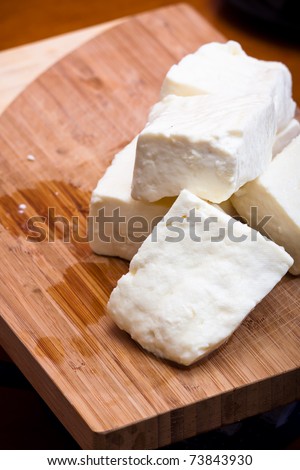 Big slices of Curd cheese on cutting board.