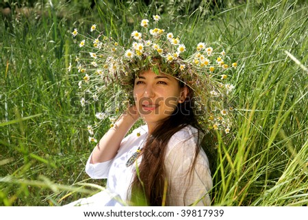 young woman on the meadow with diadem with wild flowers on
