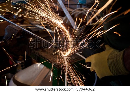 Man at work, grinding a metal bar