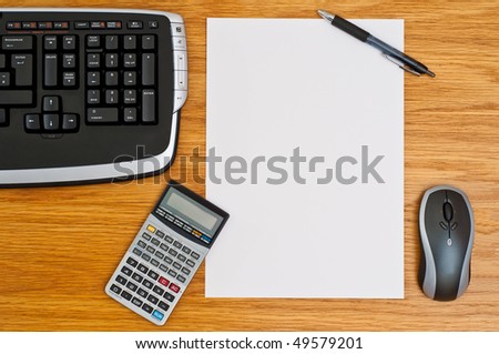 Office desk with keyboard, calculator, mouse, pen and a blank paper