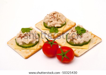 Crackers with soft cod roes, tomatoes, cucumber and cheese isolated on white