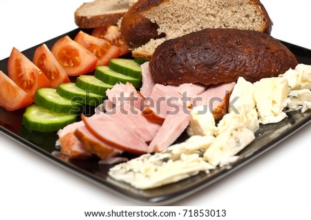 bread, ham, cheese, tomato and cucumber appetizer served on a black plate isolated on white
