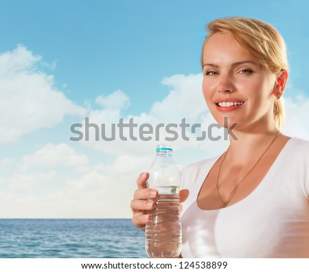 Beautiful woman smiling with water bottle in hand on tropical beach