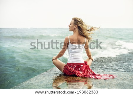 Young blonde woman meditation on the beach