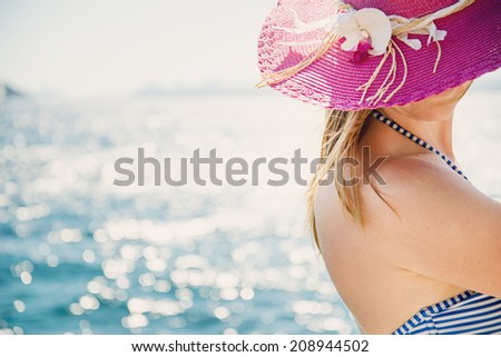Beautiful girl in a hat enjoying the sun on the beach