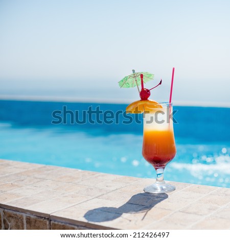 Orange cocktail near the pool at sunny day